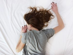Picture of a woman lying on a bed sleeping.